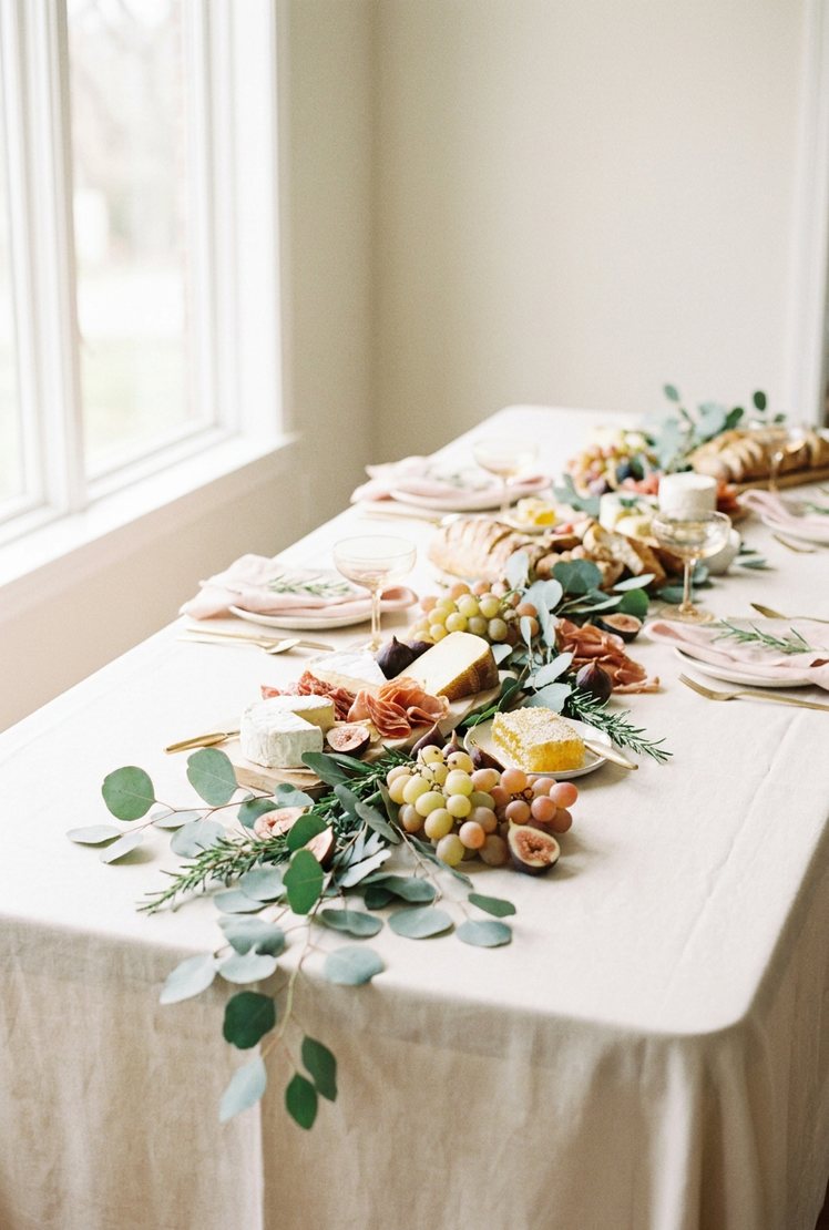 A long grazing table with greenery threaded through it